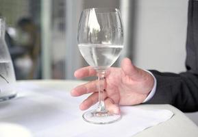 hombre alcanzando una copa de vino llena de agua foto