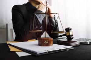 Business and lawyers discussing contract papers with brass scale on desk in office. Law, legal services, advice, justice and law concept picture with film grain effect photo