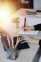 Woman accountant use calculator and computer with holding pen on photo