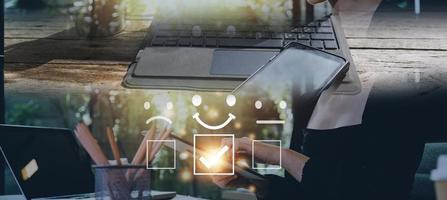 concepto de evaluación del servicio al cliente. hombre de negocios presionando el espectáculo de emoticonos de sonrisa de cara en la pantalla virtual. encuesta, sondeo o cuestionario para la experiencia del usuario o la investigación de la satisfacción del cliente. foto