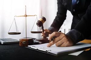 Business and lawyers discussing contract papers with brass scale on desk in office. Law, legal services, advice, justice and law concept picture with film grain effect photo