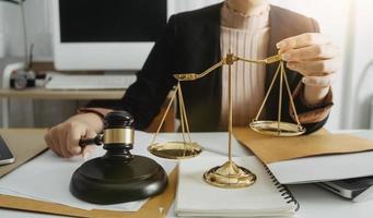 Justice and law concept.Male judge in a courtroom with the gavel, working with, computer and docking keyboard, eyeglasses, on table in morning light photo