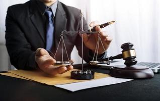 Justice and law concept.Male judge in a courtroom with the gavel, working with, computer and docking keyboard, eyeglasses, on table in morning light photo