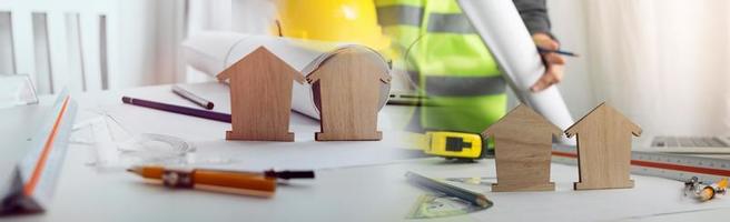 Dos colegas discutiendo el trabajo de datos y una tableta, un portátil con un proyecto arquitectónico en el sitio de construcción en un escritorio en la oficina foto