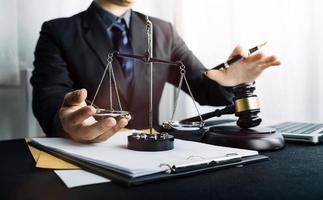 Justice and law concept.Male judge in a courtroom with the gavel, working with, computer and docking keyboard, eyeglasses, on table in morning light photo