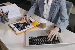 Woman accountant use calculator and computer with holding pen on photo