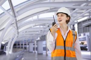 una ingeniera caucásica está usando walkie talkie mientras inspecciona el proyecto de construcción para la arquitectura moderna y el concepto de desarrollo inmobiliario foto