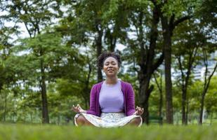 African American woman relaxingly practicing meditation in the forest to attain happiness from inner peace wisdom for healthy mind and soul photo