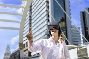 joven mujer caucásica usando gafas vr para jugar un juego de simulador de realidad virtual rodeada por un moderno edificio urbano en el centro de la ciudad