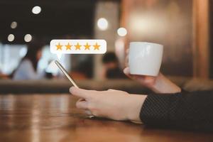 Customer hand press on smartphone screen with gold five star rating feedback icon excellent rank level for giving best score point to review the service , ranking experience, evaluate quality. photo