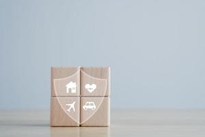 Insurance concept. Protection against a possible eventuality. House, Car, travel and Health icon on wooden block for assurance life concept. photo