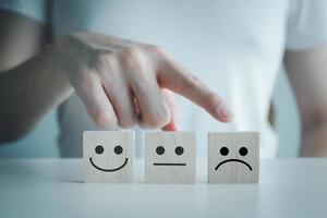 Customer service rating experience and feedback emotion and satisfaction survey and negative, neutral and positive facial expressions. hand choose sad face icon on wood cube. photo
