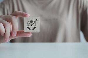 Business strategy, Action plan, Goal and target. Hand holding dart board symbols on wooden block. Goal or agenda setting in business concept. photo