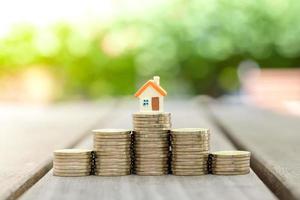 Small house model stand on top center stack of coin. Save money to get property, loan, mortgage,home interest rates, house tax, business and financial banking background. photo