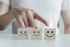 Customer service rating experience and feedback emotion and satisfaction survey with star and negative, neutral and positive facial expressions. hand choose 5 star happy smiley face icon on wood cube. photo