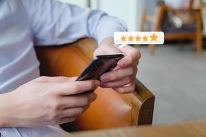 Customer hand press on smartphone screen with gold five star rating feedback icon excellent rank level for giving best score point to review the service , ranking experience, evaluate quality. photo