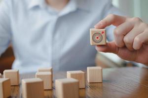 Business strategy, Action plan, Goal and target. Hand holding dart board symbols on wooden block. Goal or agenda setting in business concept. photo