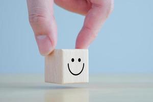 Emotion, Mental, Customer service evaluation and satisfaction survey concept. Review, Feedback. Hand holding happy face on wooden blocks. photo