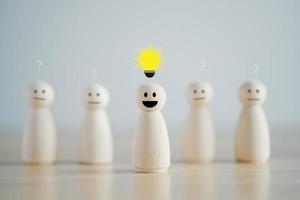 Leader with idea and innovation and creativity concept. Creative process concept and problem solution. happy face wooden human and glowing light bulb. Standing out from the crowd. photo