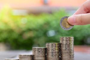 hand holding coin for insert to stack of coin. Save money and business finance concept. photo