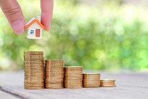 Hand holding mini house model on coins stack. Planning to buy property. Choose the best. photo