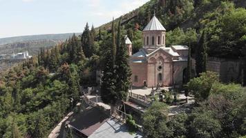 Aerial ascending view St. David's Church called Mama daviti on the slope of Mount Mtatsminda. Mtatsminda Pantheon of Writers and Public Figures is located around St. David's church video