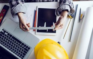 Two colleagues discussing data working and tablet, laptop with on on architectural project at construction site at desk in office photo