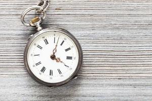 reloj de bolsillo vintage en mesa de madera gris foto