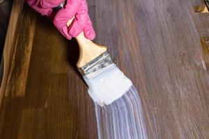 gloved hand varnishes a stained wooden board photo