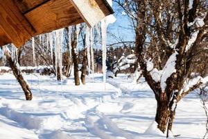 icicles on the edge of roof of wooden cottage photo