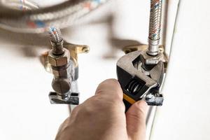 plumber hand fixes connection of tap by wrench photo