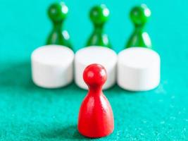 red pawn in front of three green pawns with tables photo