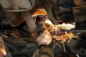 serviceman cleans muffler pipe by angle grinder photo