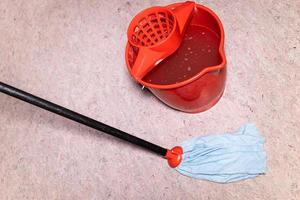 mop washes linoleum floor near red bucket photo