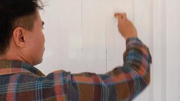 un' pittore è pittura bianca con un' dipinto tracciare su il porta di un' bianca di legno Casa. video