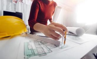 Two colleagues discussing data working and tablet, laptop with on on architectural project at construction site at desk in office photo