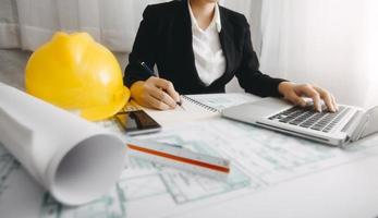 Two colleagues discussing data working and tablet, laptop with on on architectural project at construction site at desk in office photo