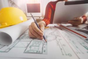 Two colleagues discussing data working and tablet, laptop with on on architectural project at construction site at desk in office photo