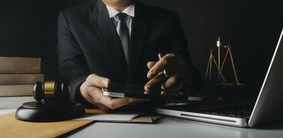 Justice and law concept.Male judge in a courtroom with the gavel, working with, computer and docking keyboard, eyeglasses, on table in morning light photo