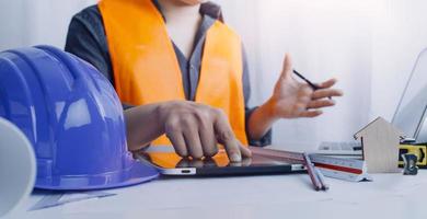 Two colleagues discussing data working and tablet, laptop with on on architectural project at construction site at desk in office photo