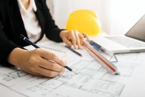 Two colleagues discussing data working and tablet, laptop with on on architectural project at construction site at desk in office photo