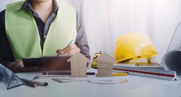 Two colleagues discussing data working and tablet, laptop with on on architectural project at construction site at desk in office photo