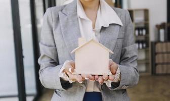 Modeling wooden houses and coins and dollars placed on wooden tables,preparation concept for house model purchase and the fastest growing real estate economy,moving home or renting property via agent photo