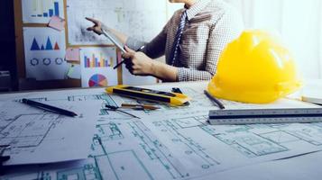 Two colleagues discussing data working and tablet, laptop with on on architectural project at construction site at desk in office photo