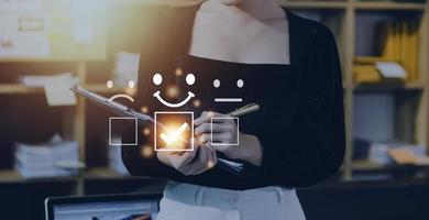 Customer service evaluation concept. Businessman pressing face smile emoticon show on virtual screen. Survey, poll or questionnaire for user experience or customer satisfaction research. photo