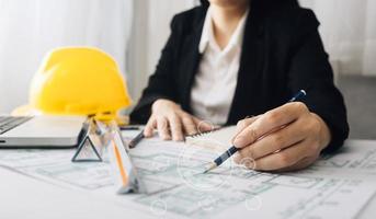 Two colleagues discussing data working and tablet, laptop with on on architectural project at construction site at desk in office photo