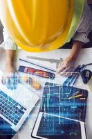 Two colleagues discussing data working and tablet, laptop with on on architectural project at construction site at desk in office photo