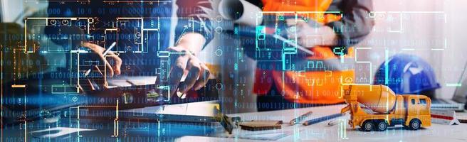 Dos colegas discutiendo el trabajo de datos y una tableta, un portátil con un proyecto arquitectónico en el sitio de construcción en un escritorio en la oficina foto