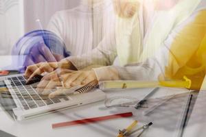 business hand working and laptop with on on architectural project at construction site at office desk in office photo