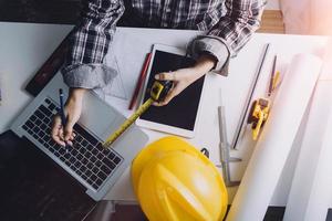 Two colleagues discussing data working and tablet, laptop with on on architectural project at construction site at desk in office photo